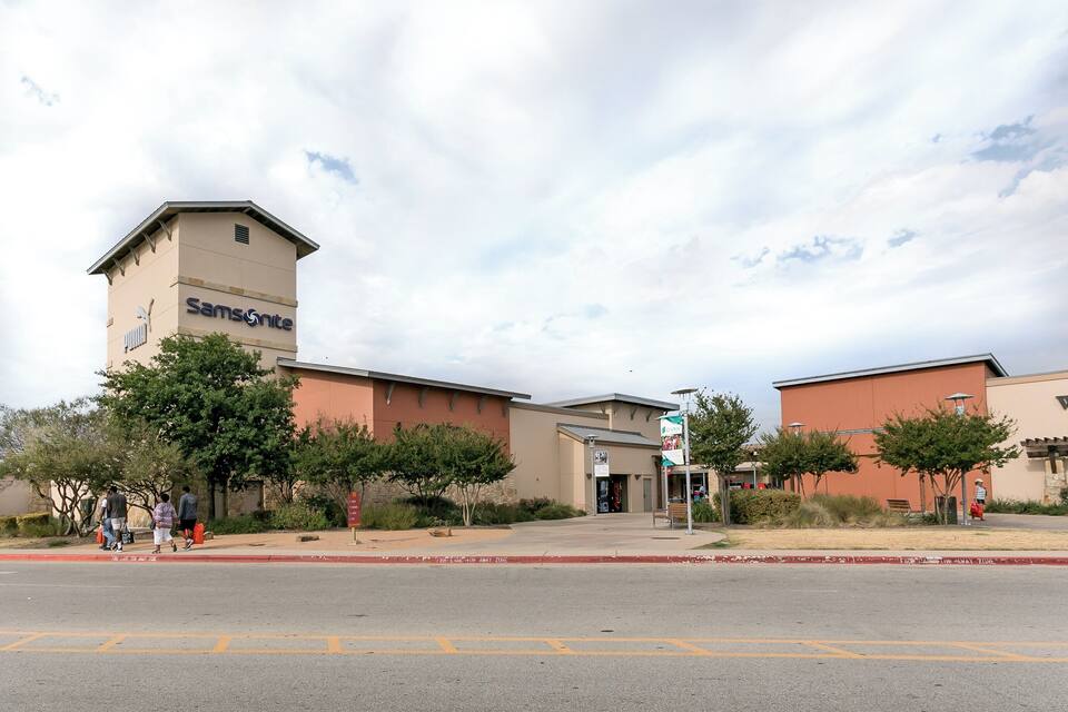 A building with a tower labeled "SamsNite" and a parking lot with people walking.