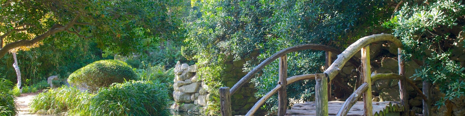 A stone bridge over a pond in a lush garden.