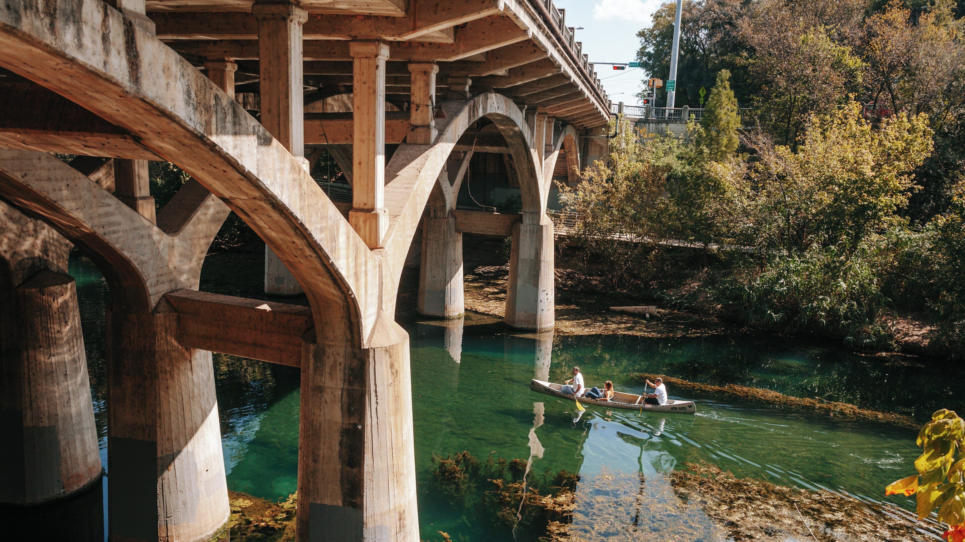 Canoeing under the iconic bridge at Zilker Park in Barton Hills, Austin during a sunny afternoon