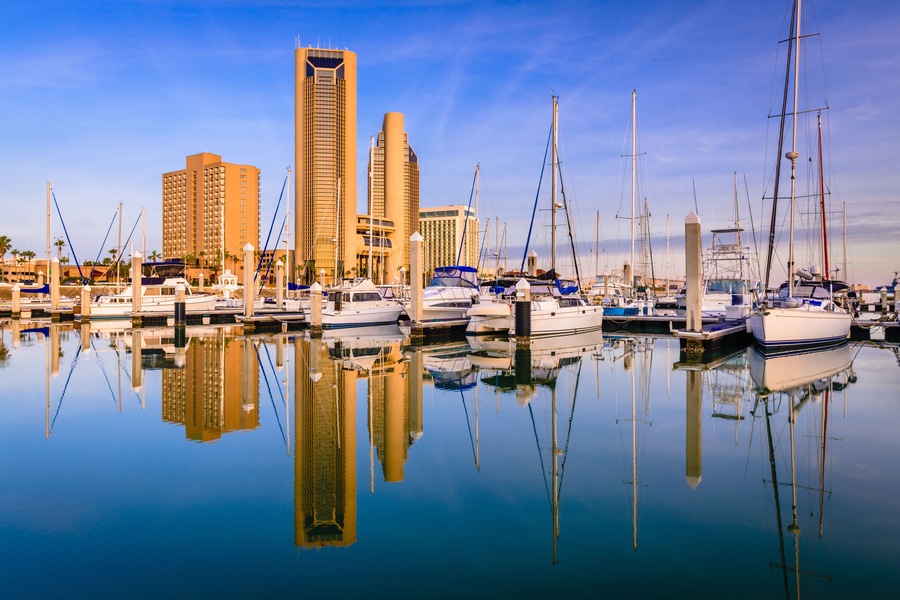 Uma marina com barcos, um edifício alto e um céu azul límpido.