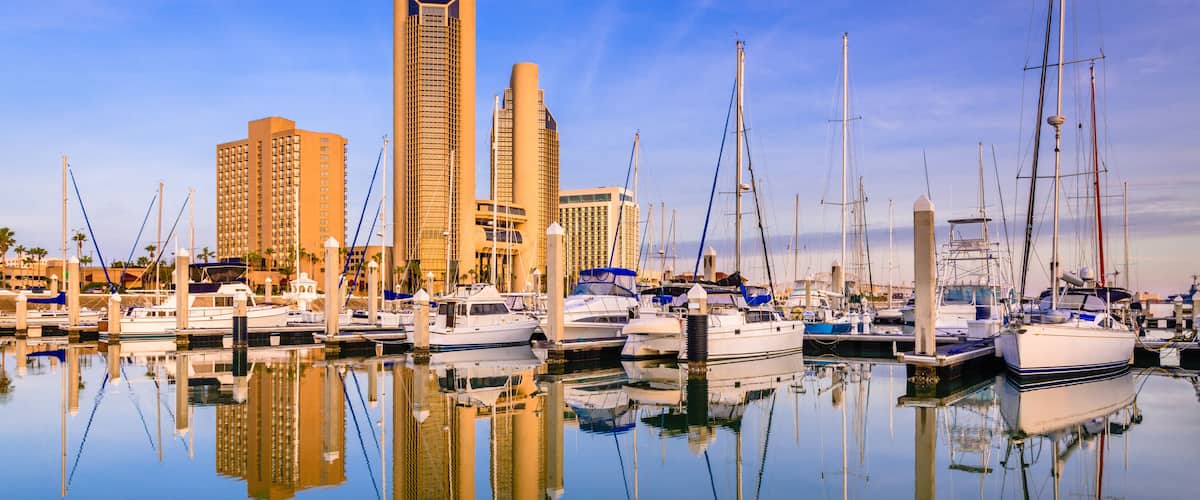 A marina with boats, a tall building, and a clear blue sky.