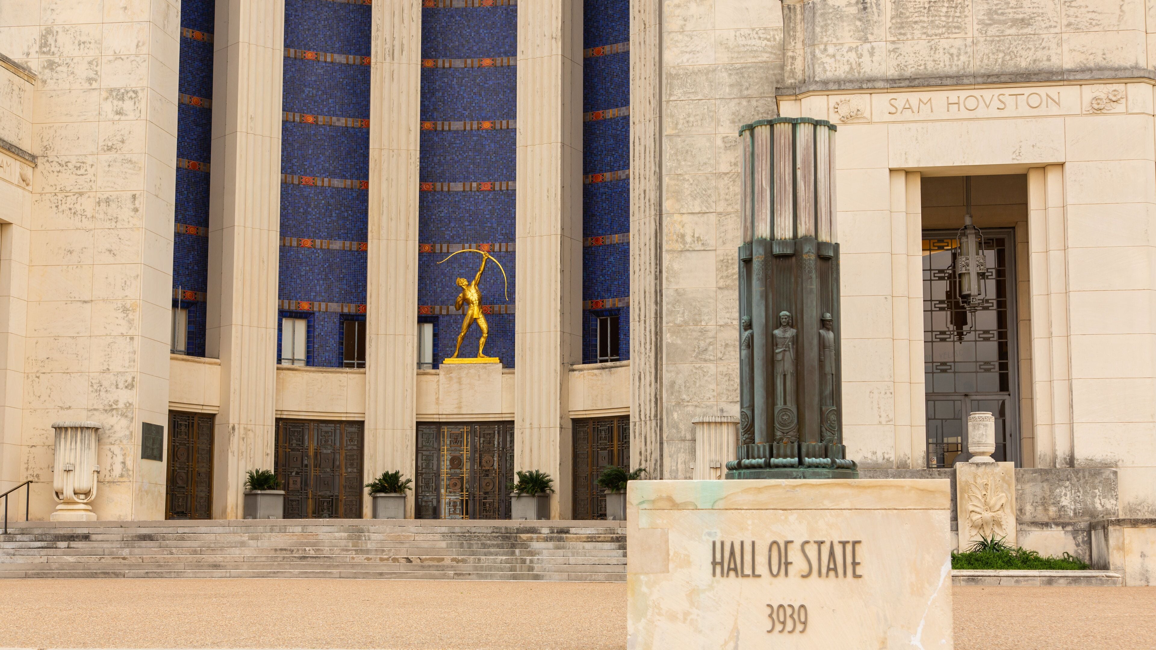 A building with columns, a statue, and a sign that reads "Hall of State 3939".