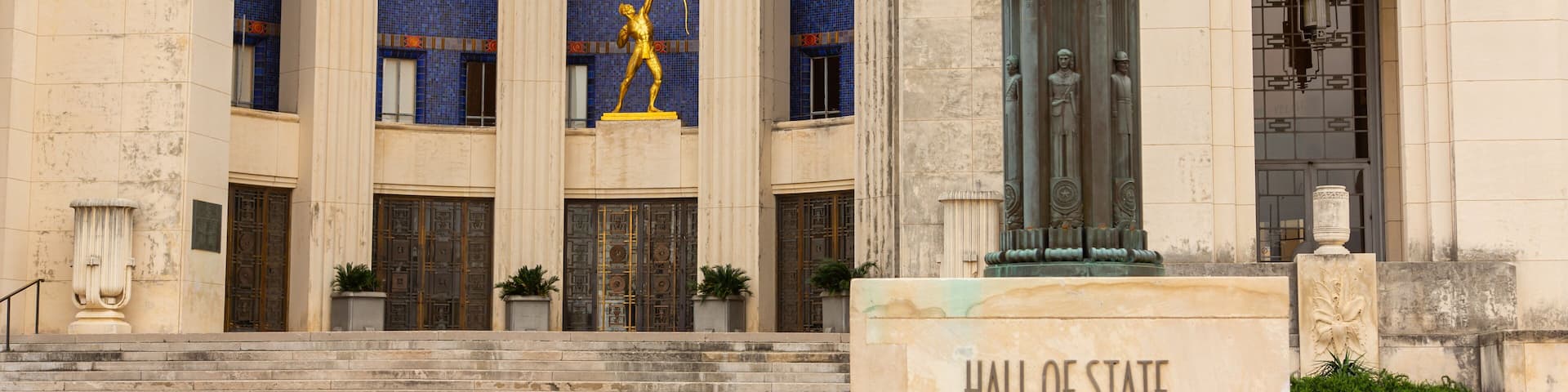 A building with columns, a statue, and a sign that reads "Hall of State 3939".