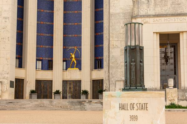 En bygning med søjler, en statue og et skilt, der står 'Hall of State 3939'.
