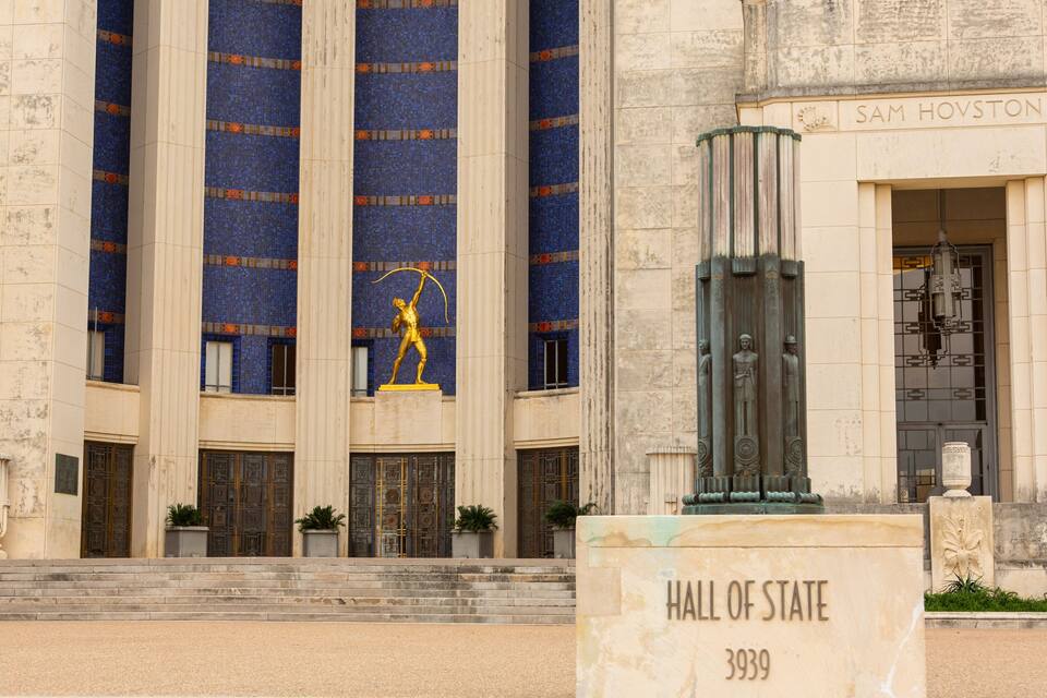A building with columns, a statue, and a sign that reads "Hall of State 3939".