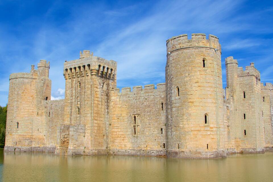 Un vaste château médiéval doté de nombreuses tours et entouré de douves.
