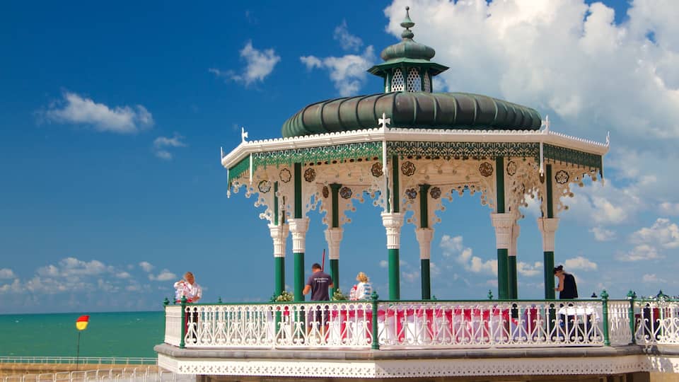 A gazebo with ornate white and green detailing, set against a clear blue sky.