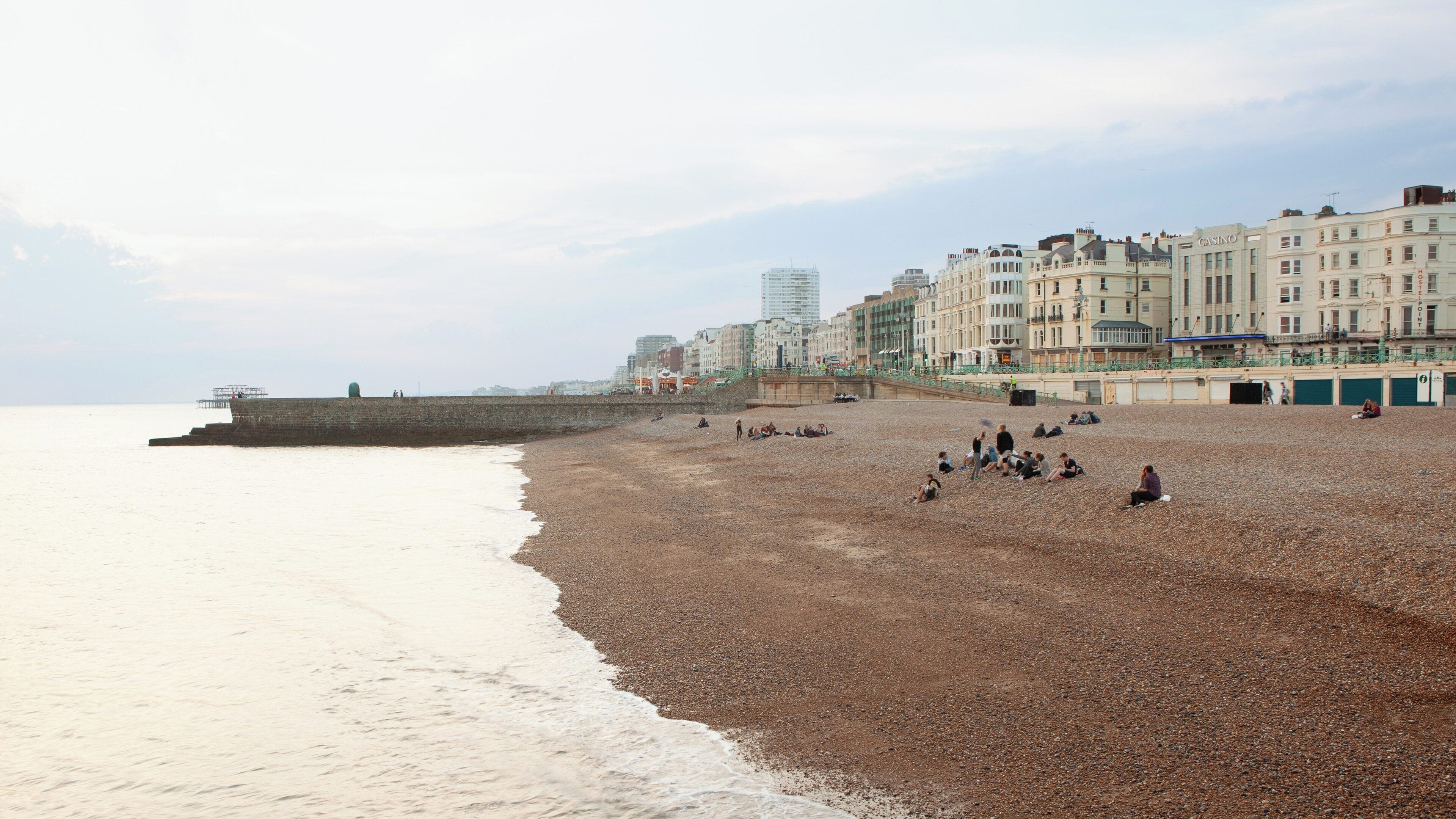 Brighton Beach at Kemptown, England showcases a tranquil shoreline filled with visitors enjoying the calm atmosphere and beautiful coastal views in the early evening