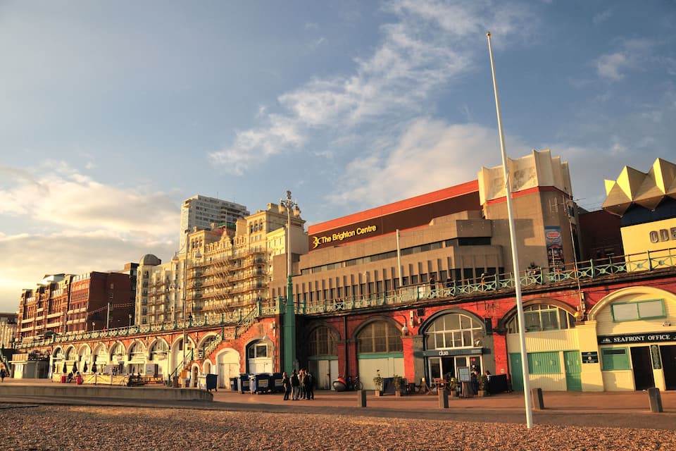 Das Brighton Centre, ein historisches Gebäude mit einer roten und weißen Fassade, bogenförmigen Fenstern und einem grünen Vordach.