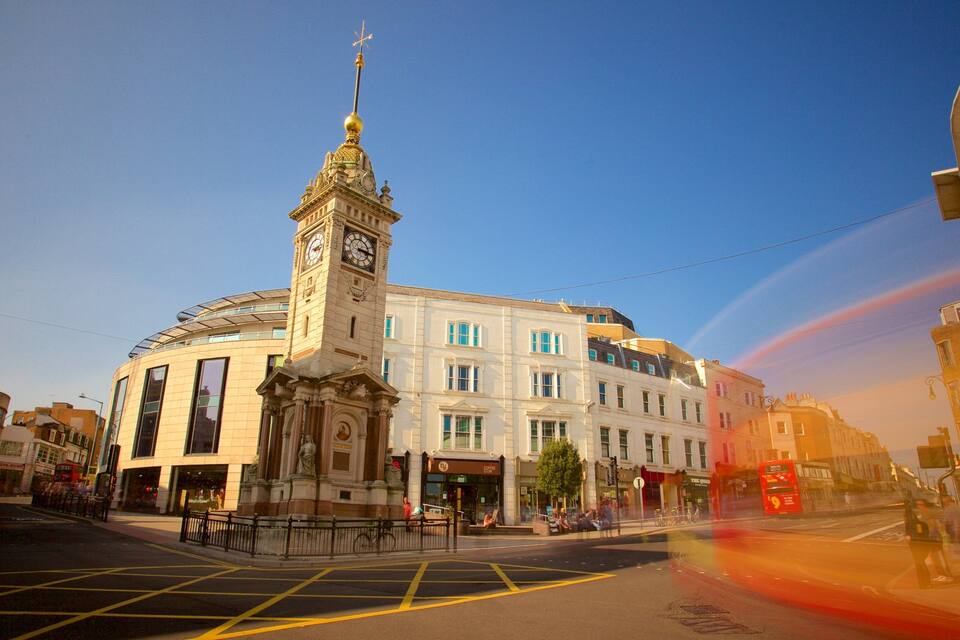 A historic building with a clock tower, a roundabout, and a tram line.