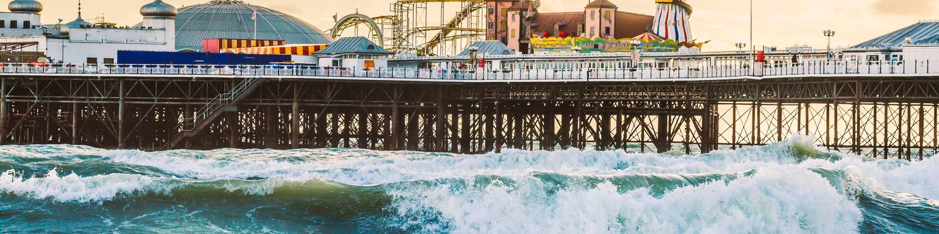 Brighton Pier, Brighton, Sussex, Britain on a storm evening at dusk as the sun is setting. There are high waves and surf on the beach
