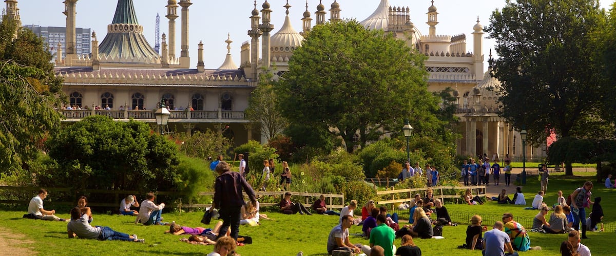 Un parc où des personnes se détendent sur l’herbe, avec, en arrière-plan, un grand bâtiment doté de coupoles et de minarets.
