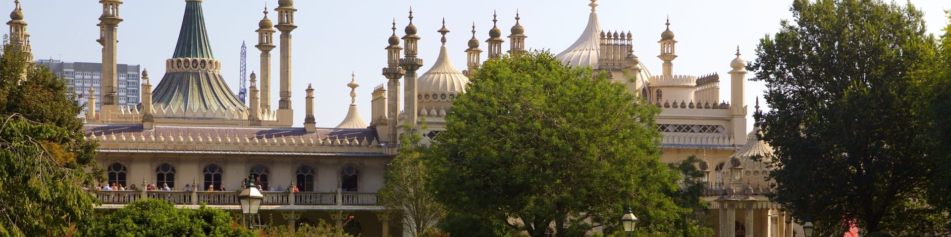 A park with people relaxing on the grass, a large building with domes and minarets in the background.