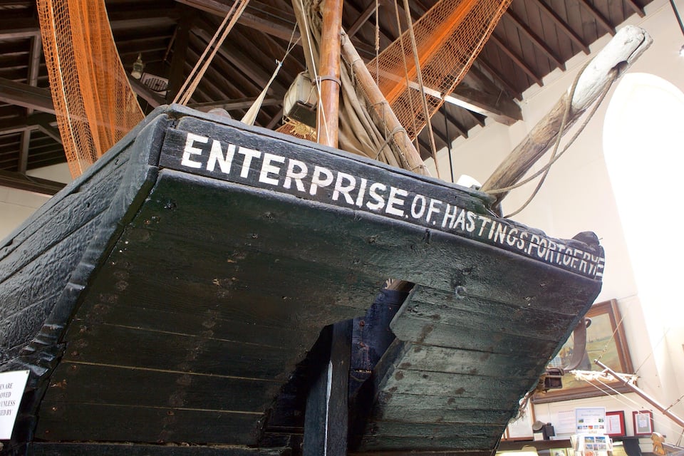 A ship's bow with the text "ENTERPRISE OF HASTINGS PORT OF HASTINGS" and a sign stating "CHILDREN ARE NOT ALLOWED ON BOARD UNLESS ACCOMPANIED BY AN ADULT".