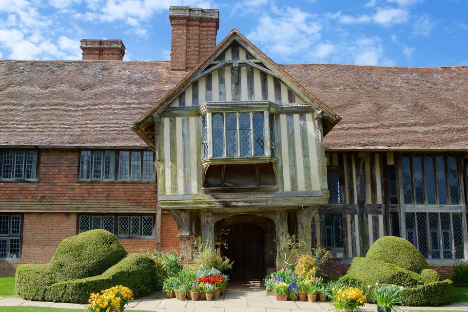 A Tudor-style building with a steeply pitched roof, large windows, and a symmetrical facade.