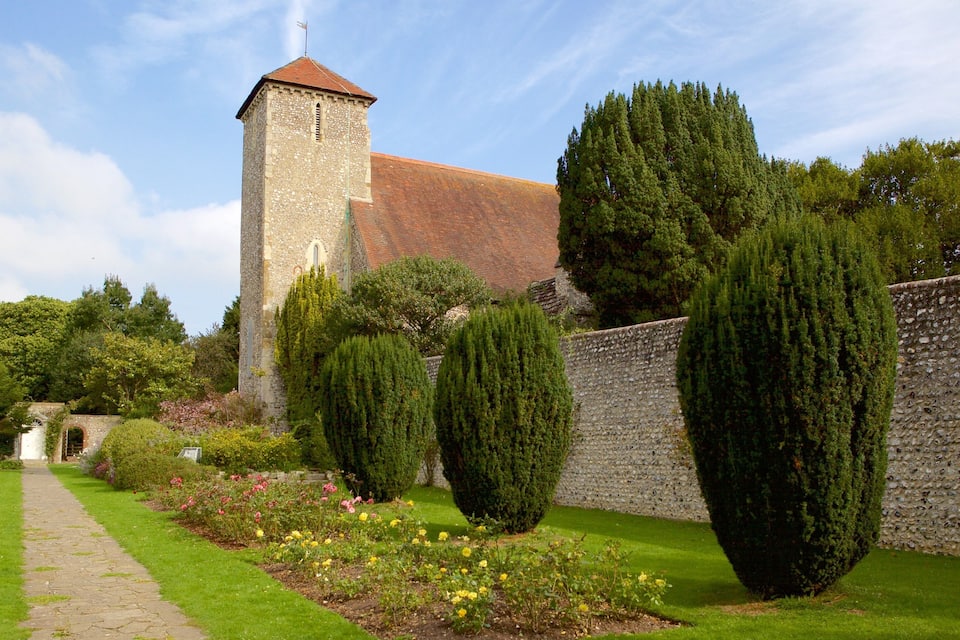 A historic stone tower, a well-maintained garden with roses, and a brick wall.