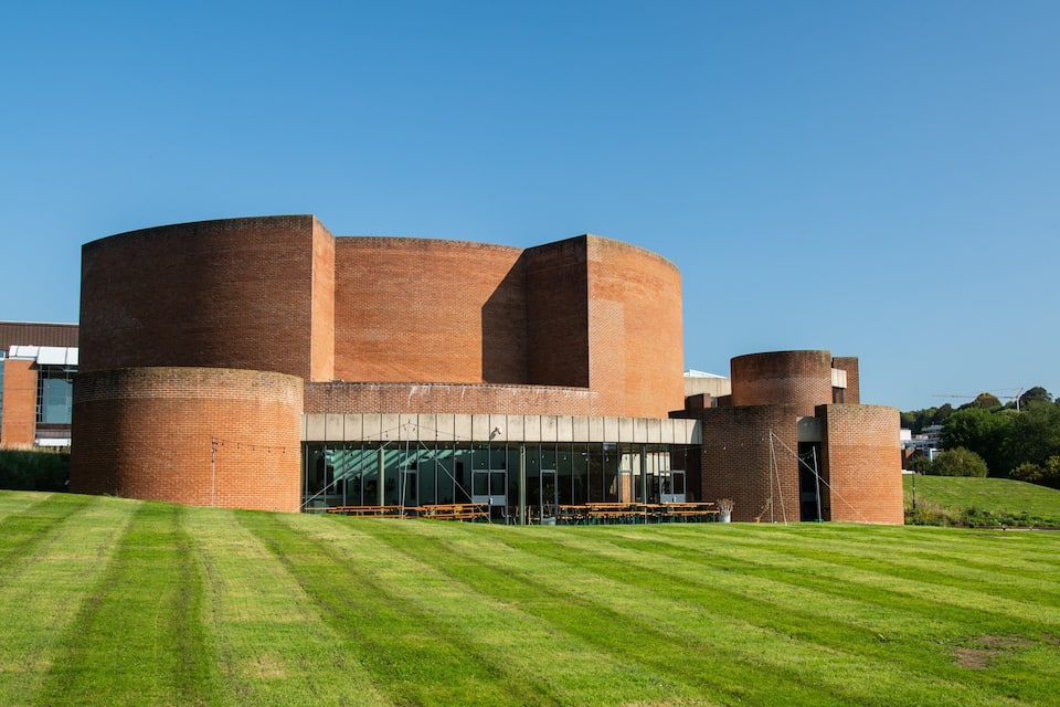 Een modern gebouw met cilindervormige constructies en een gazon ervoor.