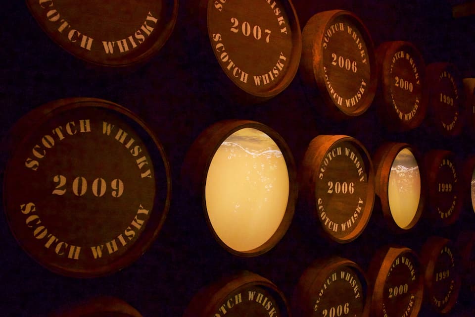 Una pared de barriles de whisky con etiquetas que marcan los años de 1999 a 2009.