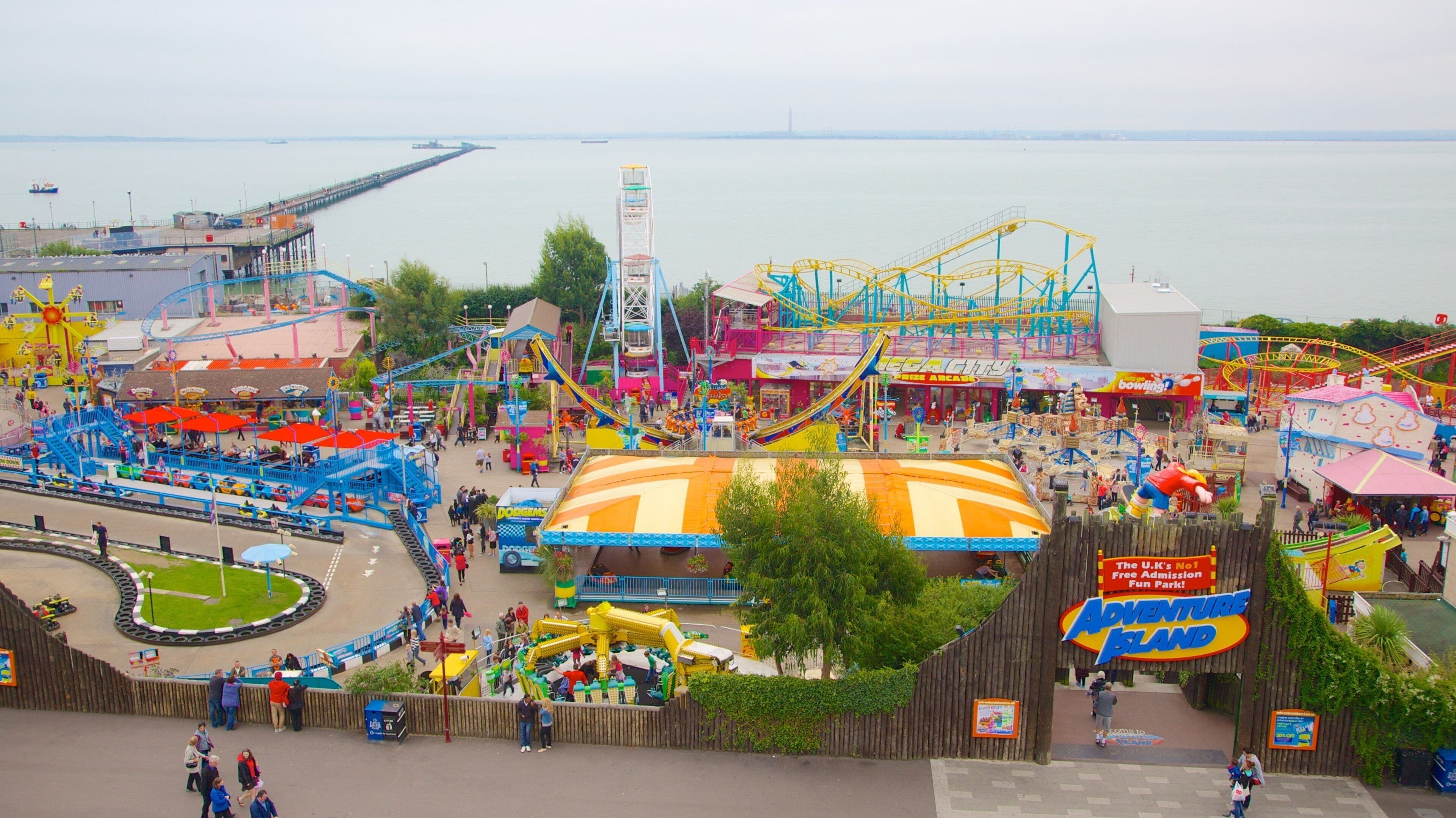 An amusement park with roller coasters, a Ferris wheel, and a large yellow building.