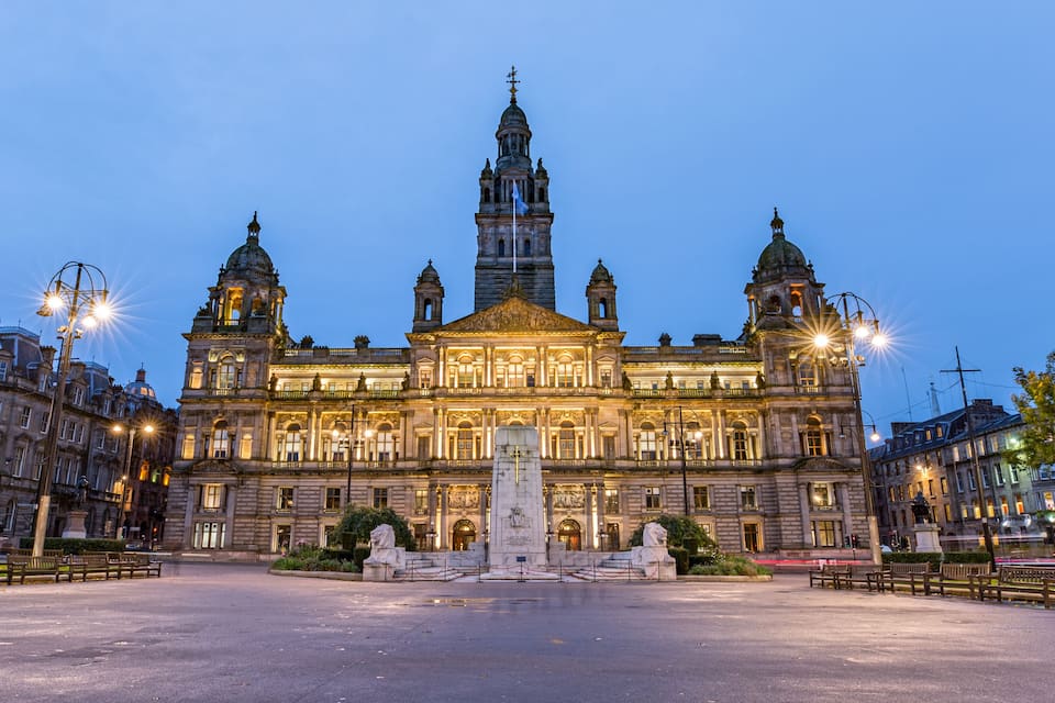 Ein prächtiges, historisches Gebäude mit mehreren Kuppeln und Türmen, einem zentralen Denkmal und einem gut beleuchteten Platz.
