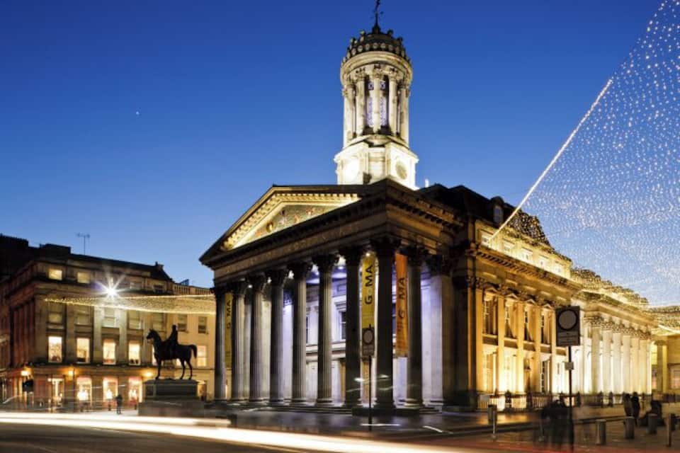 A classical building with columns and a tower, illuminated at night.