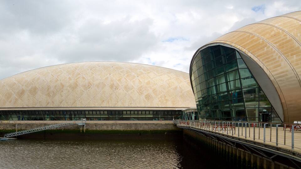 A modern architectural structure with a large, curved, cream-colored dome and a glass facade.