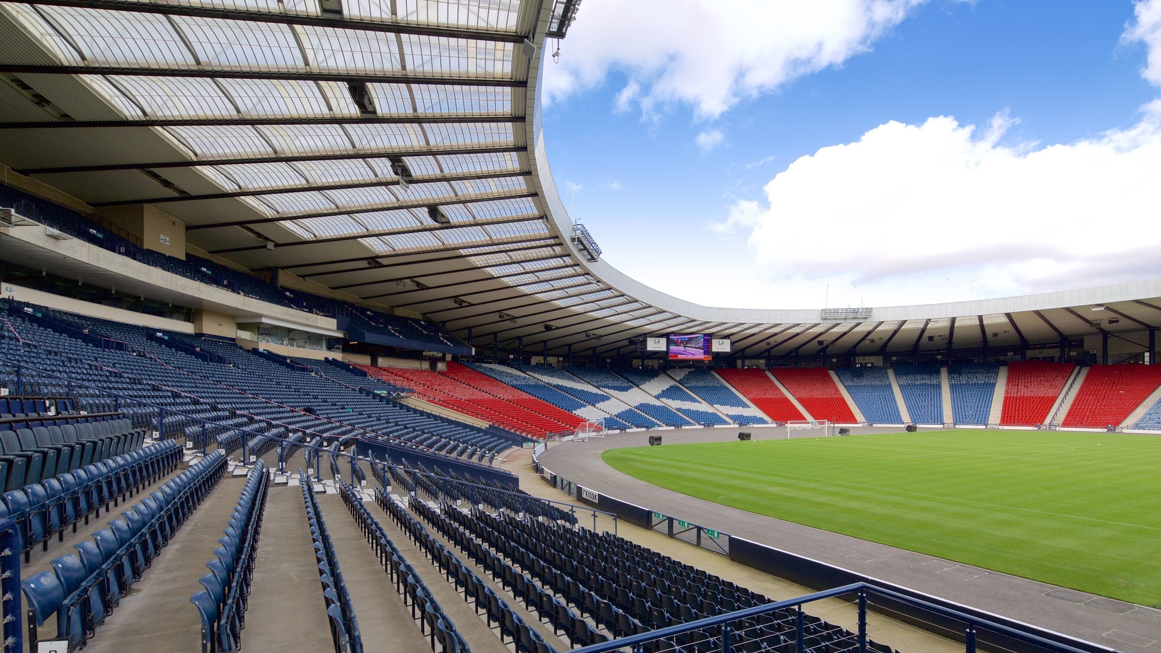 Un grand stade vide, doté de gradins et d’un toit incurvé.