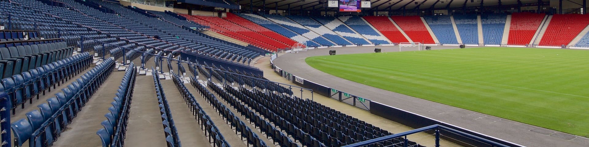 A large, empty stadium with tiered seating and a curved roof.