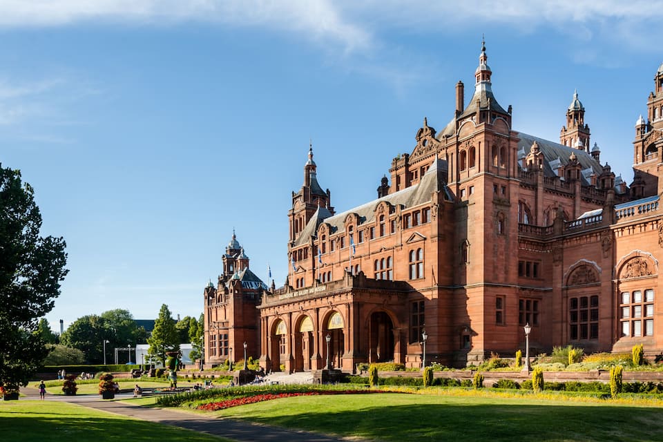 Ein historisches Gebäude mit aufwendiger Architektur, einem gepflegten Garten und blauem Himmel.