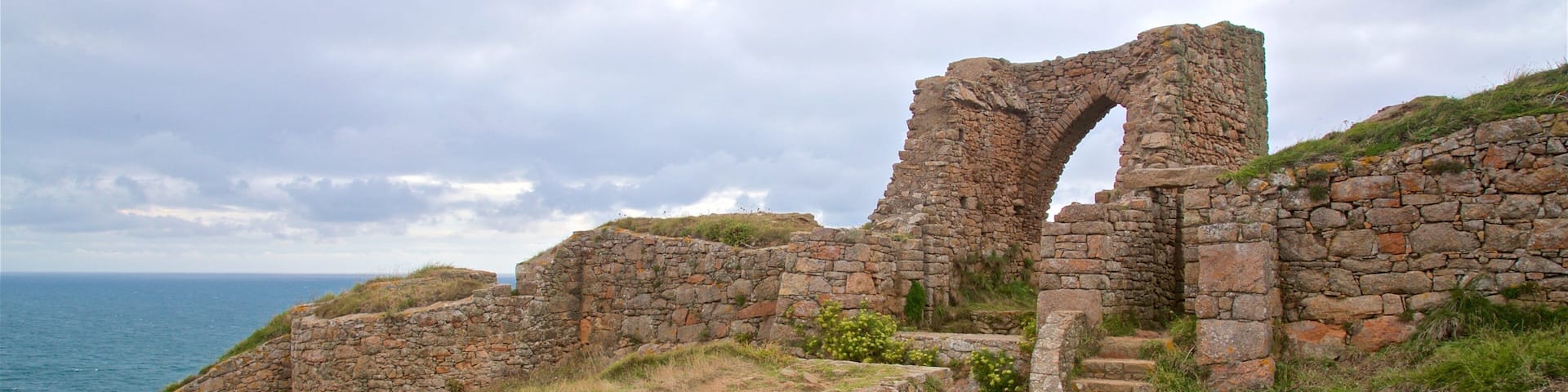 A coastal stone structure with a large archway and steps leading up to it.