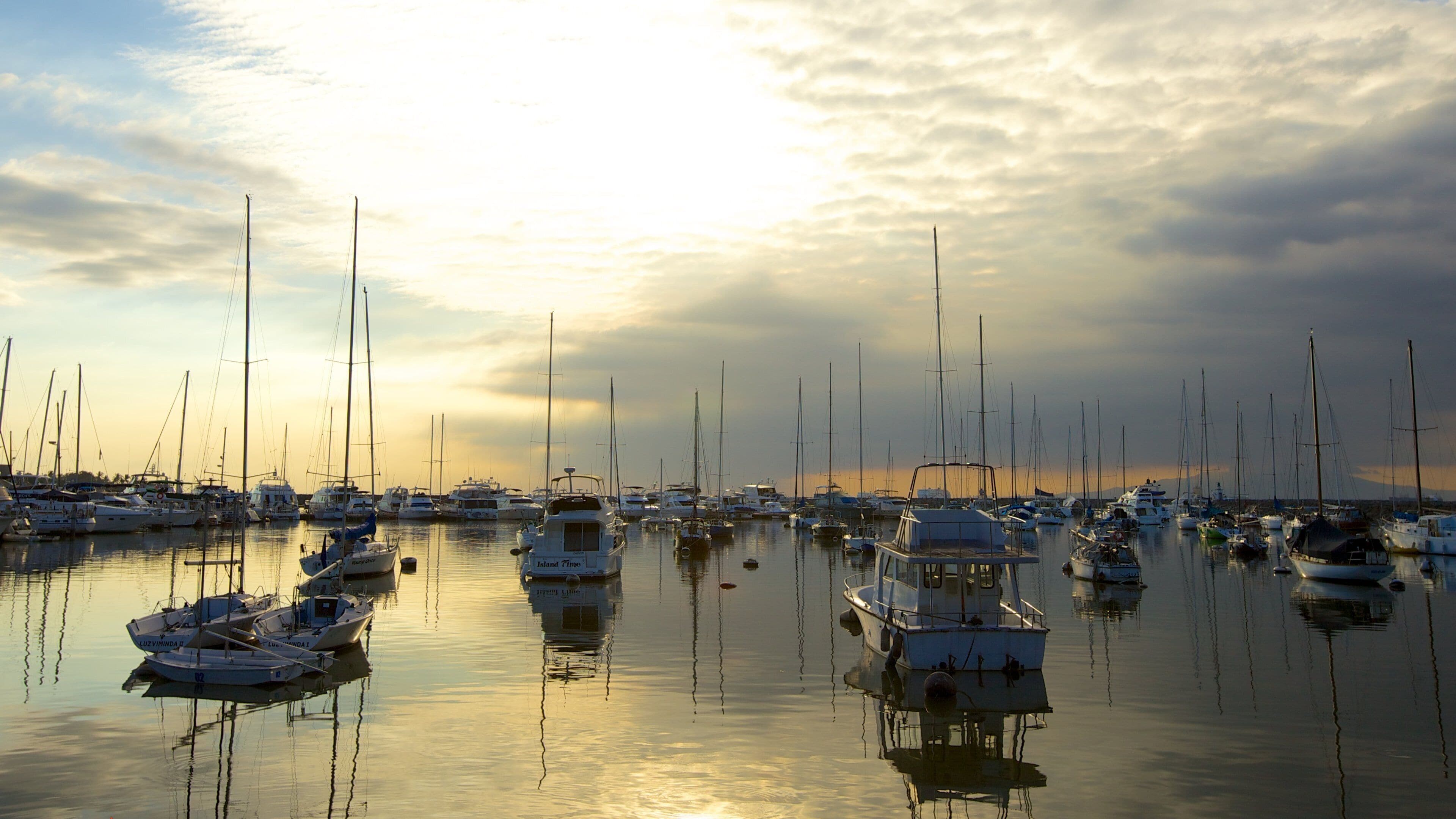 Una marina piena di vele e yacht al tramonto.