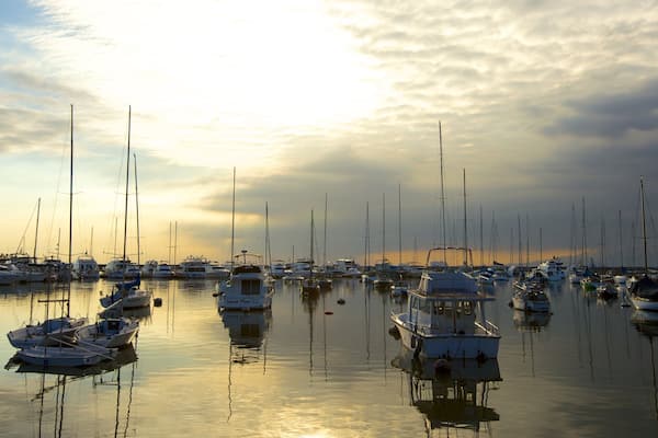 Un port de plaisance rempli de voiliers et de yachts, au coucher du soleil.