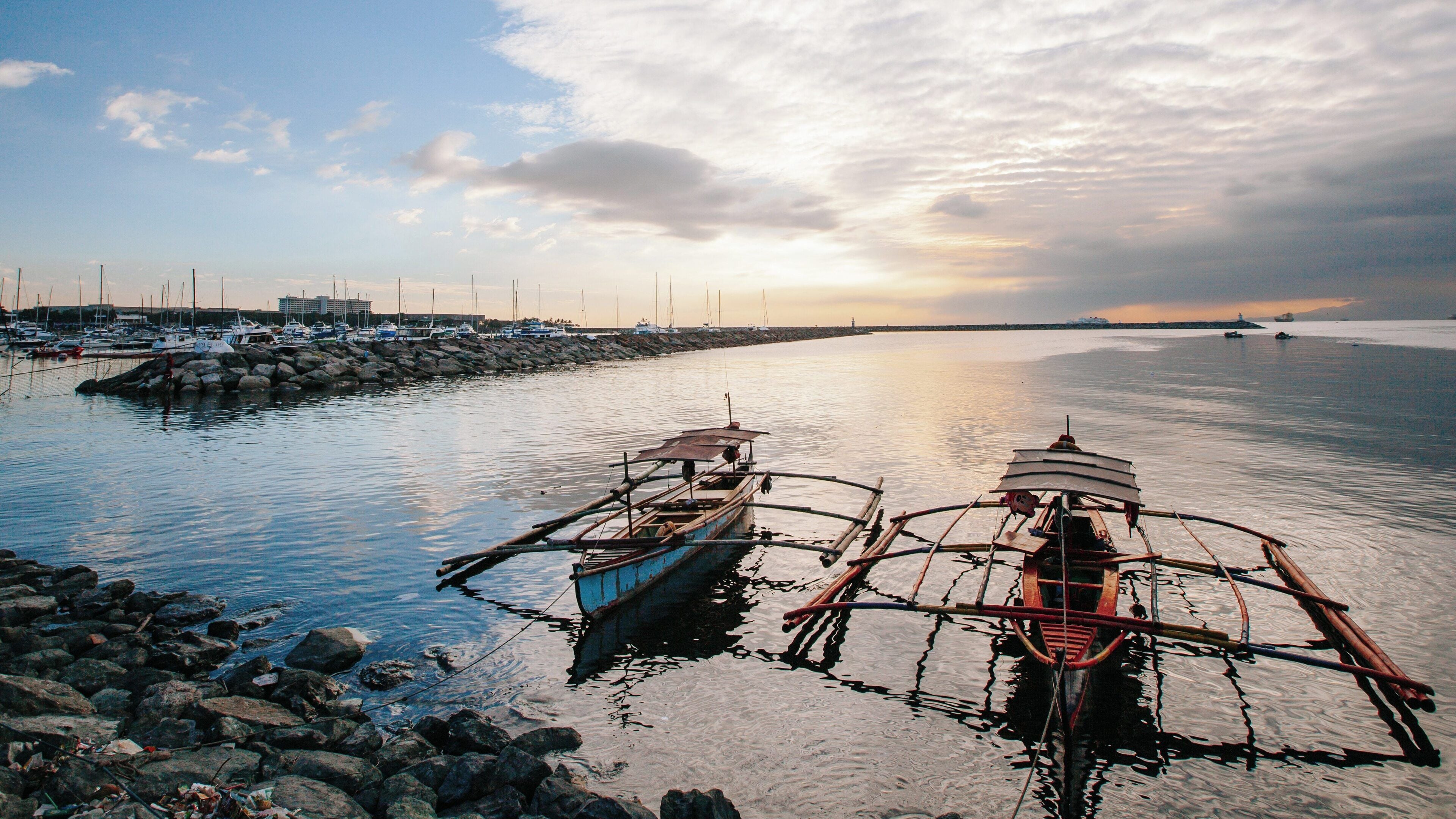 Beautiful sunset view at Baywalk in Ermita Night District, Manila, showcasing traditional boats and tranquil waters