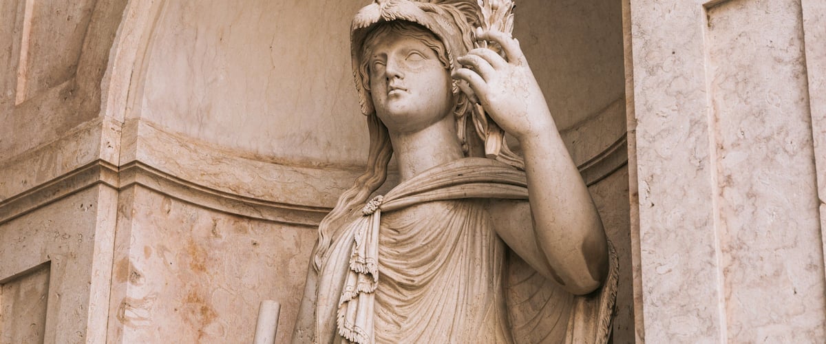 A marble statue of a woman with a laurel wreath, standing in a classical architectural setting.