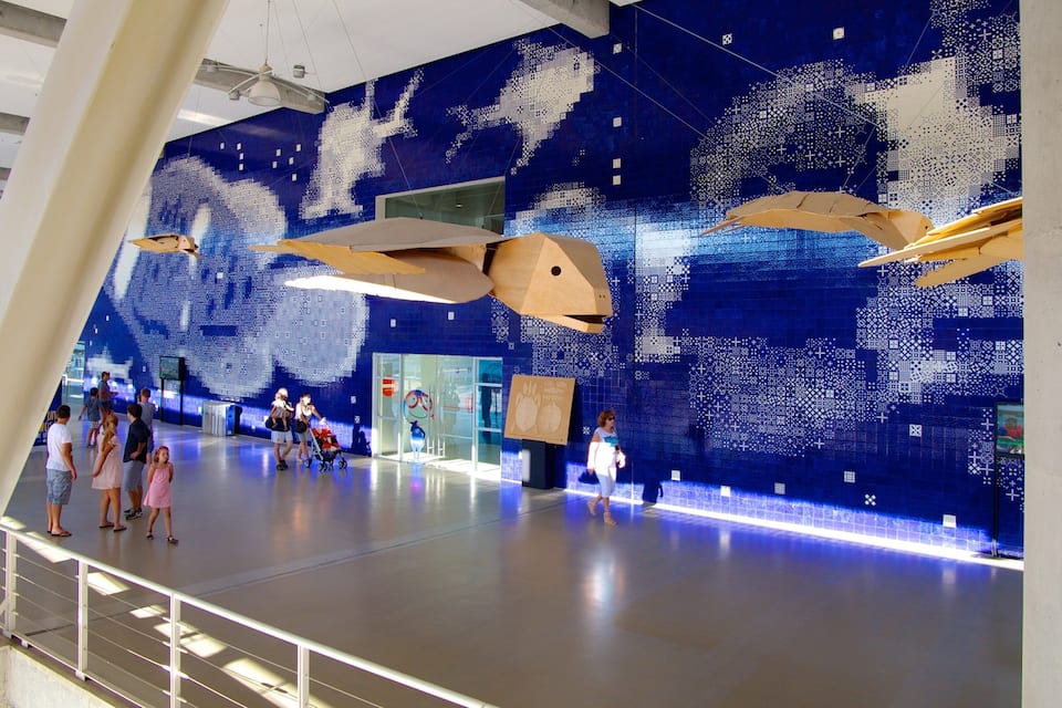 A modern indoor space with a large blue mosaic wall and wooden sculptures.
