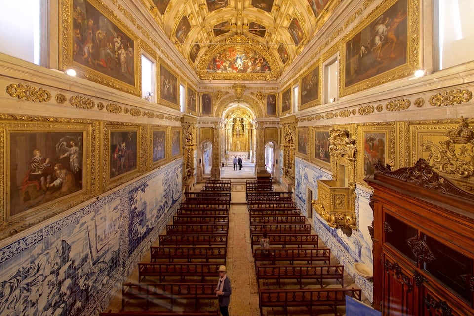 Interior de igreja ornamentado, com fileiras de bancos, afrescos detalhados e um altar central.