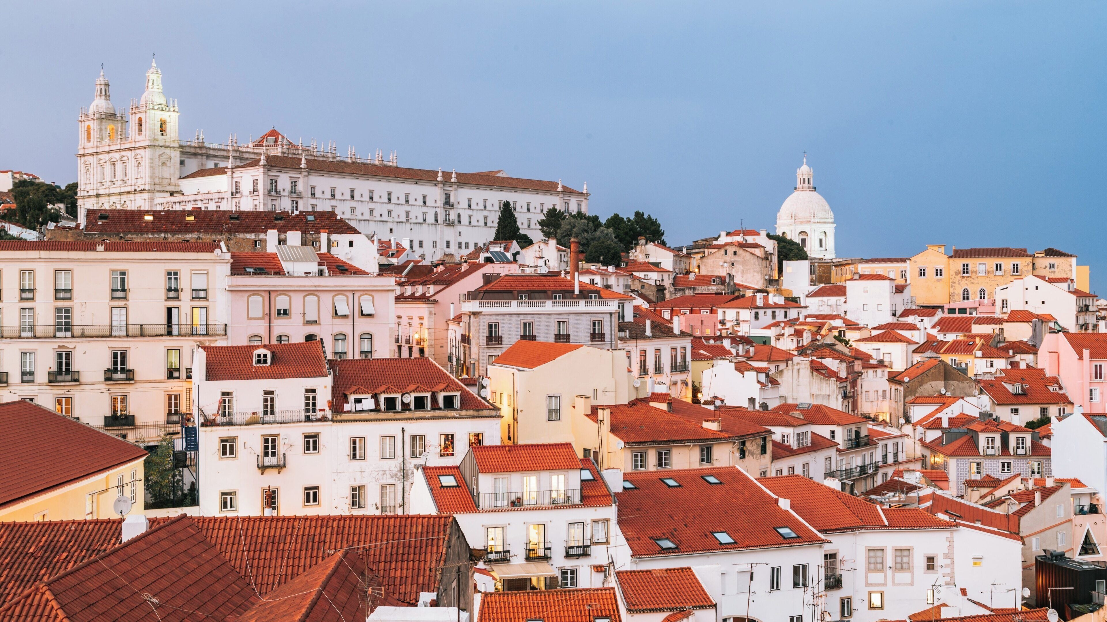 Views from Miradouro de Santa Luzia showcase the colorful rooftops and historic architecture of Alfama in Lisbon during a beautiful evening sky