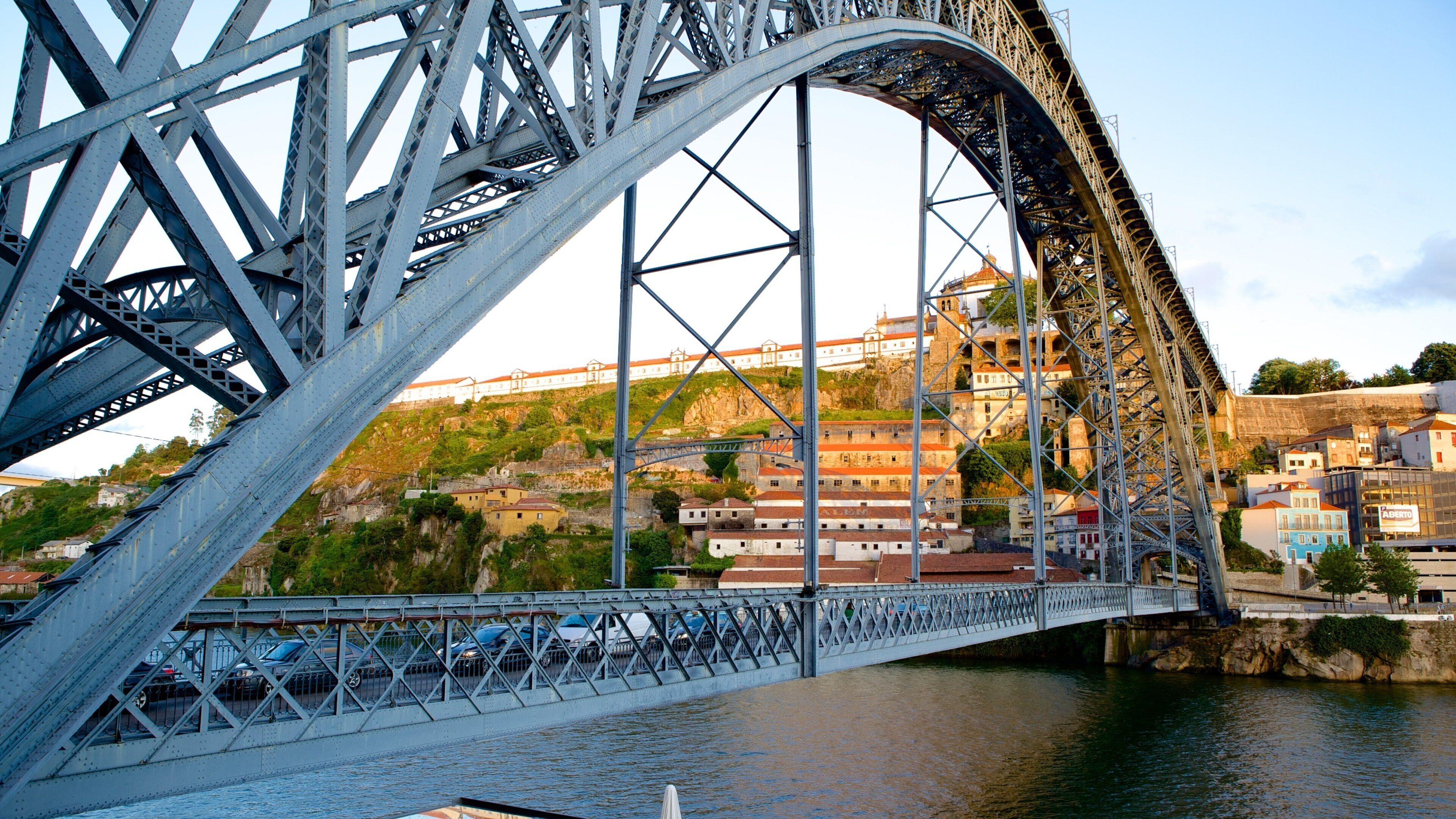 A steel bridge with a river below and buildings in the background.