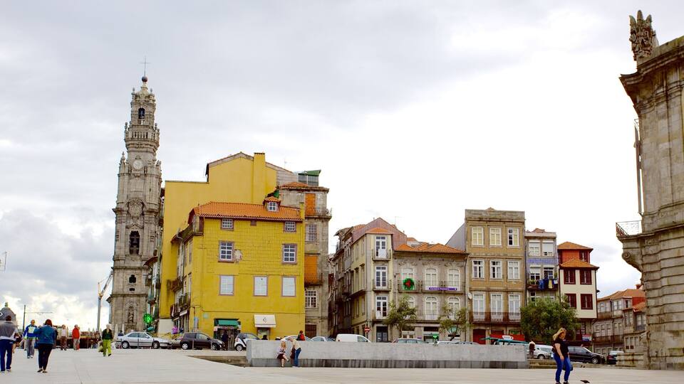 A historic square with a prominent clock tower, colorful buildings, and a statue.