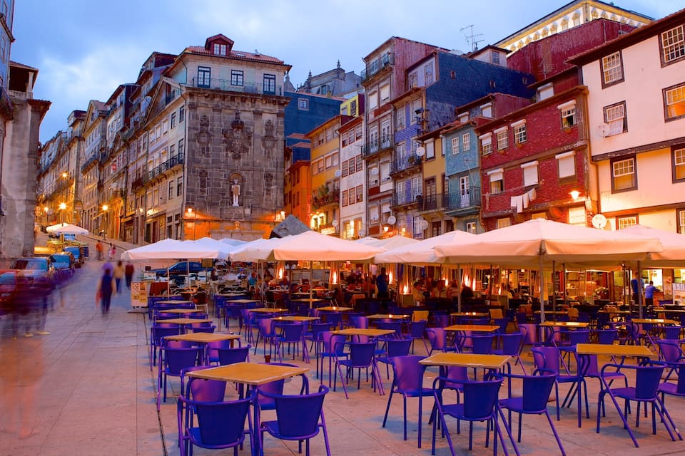 A vibrant street lined with colorful buildings and outdoor seating areas with umbrellas.