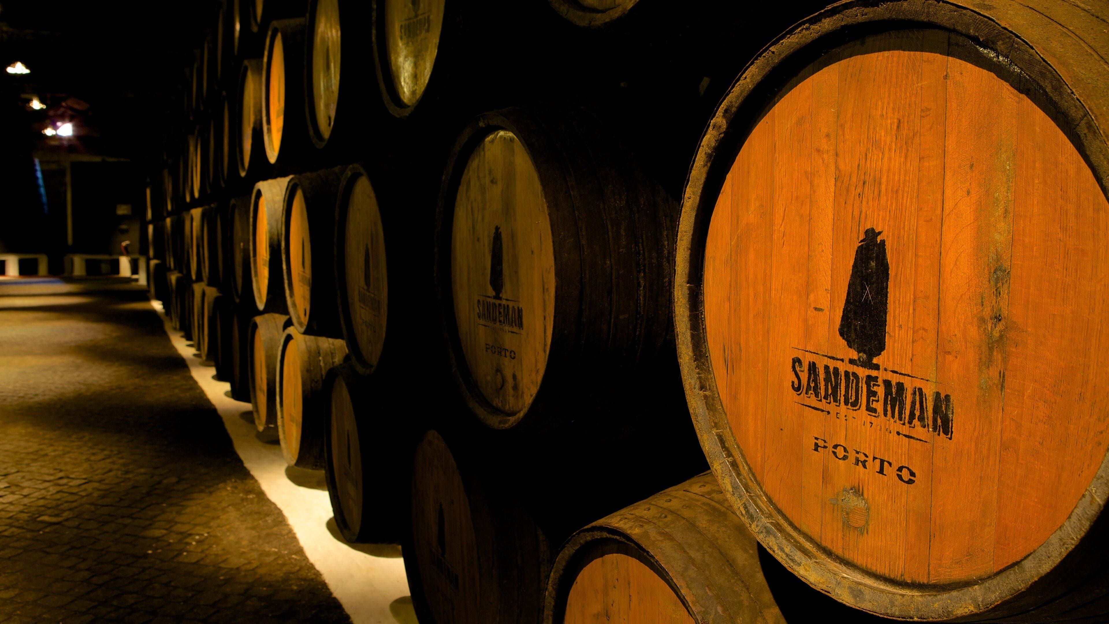 Wooden barrels stacked in rows, with the brand name "SANDEMANN" visible on the barrels.
