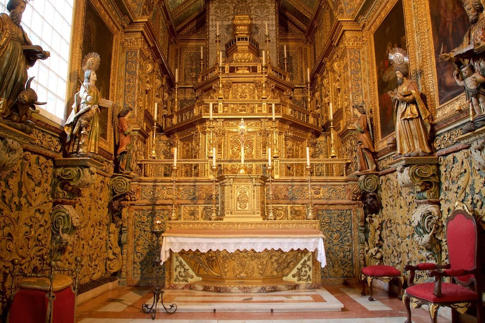 L’intérieur d’une église richement décorée, avec des ornements dorés, un autel central et des chaises rouges.