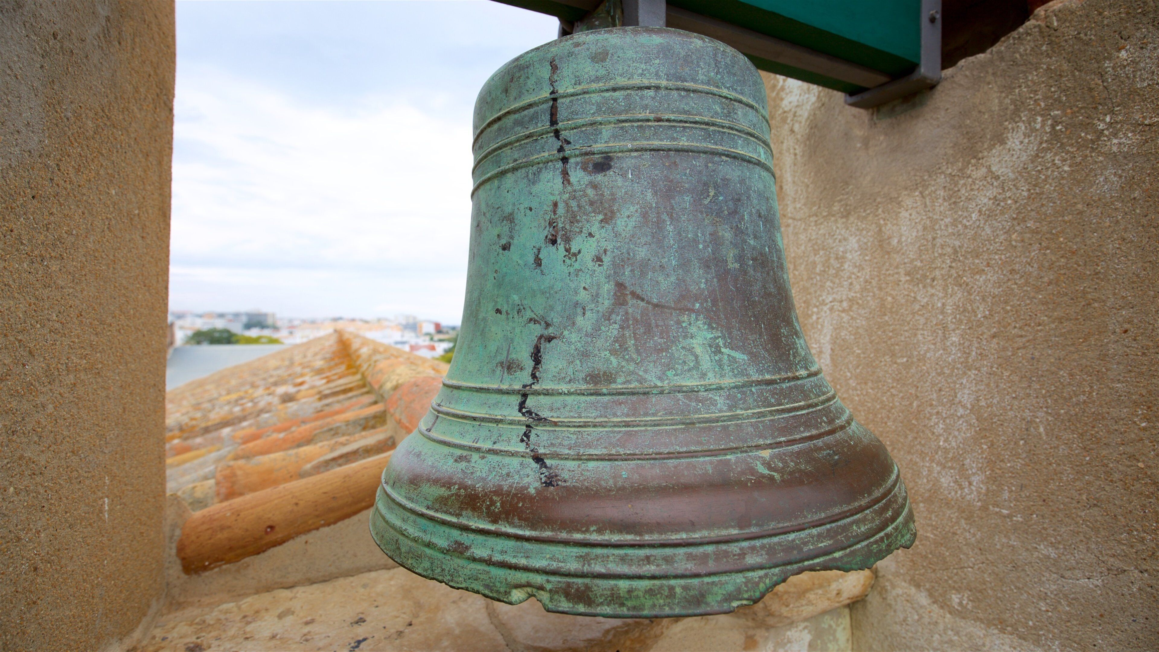 A large, weathered bell hanging from a stone structure.