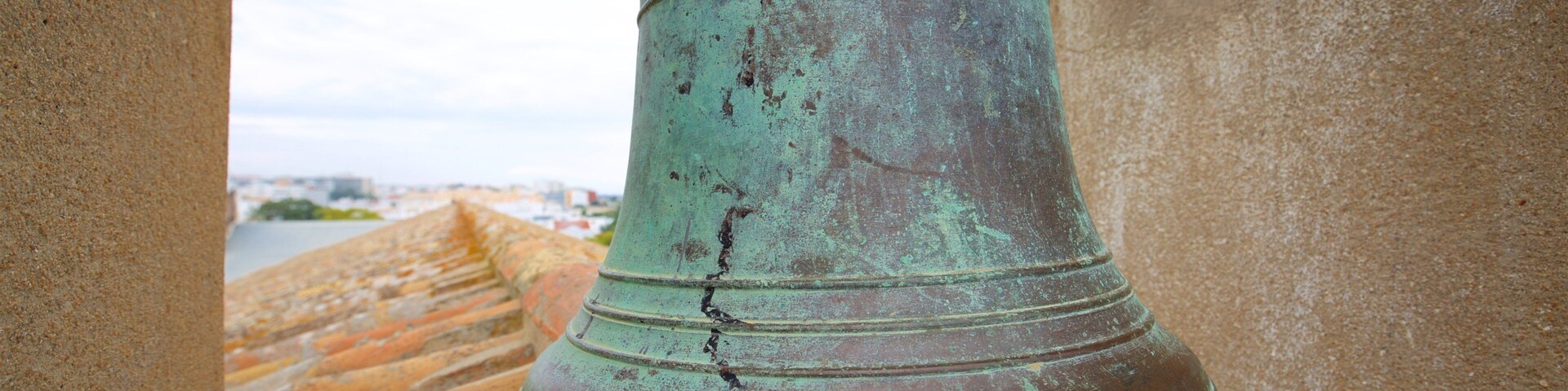 A large, weathered bell hanging from a stone structure.