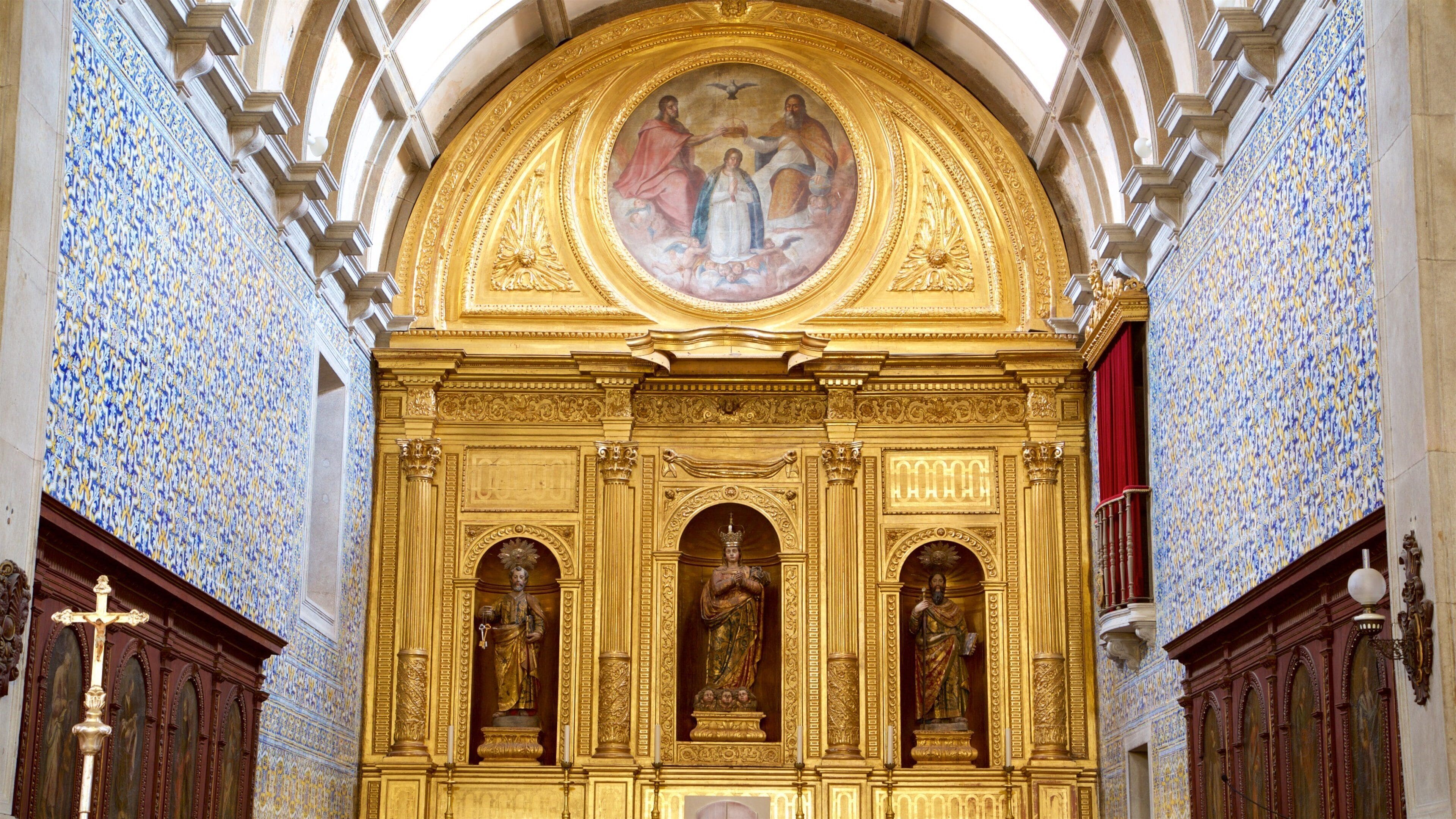 A church interior with ornate golden decorations, a large circular painting above the altar, and blue and white patterned walls.