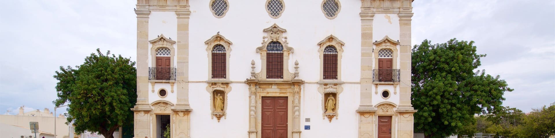 A historic church with two bell towers, a central facade with decorative elements, and a clock.