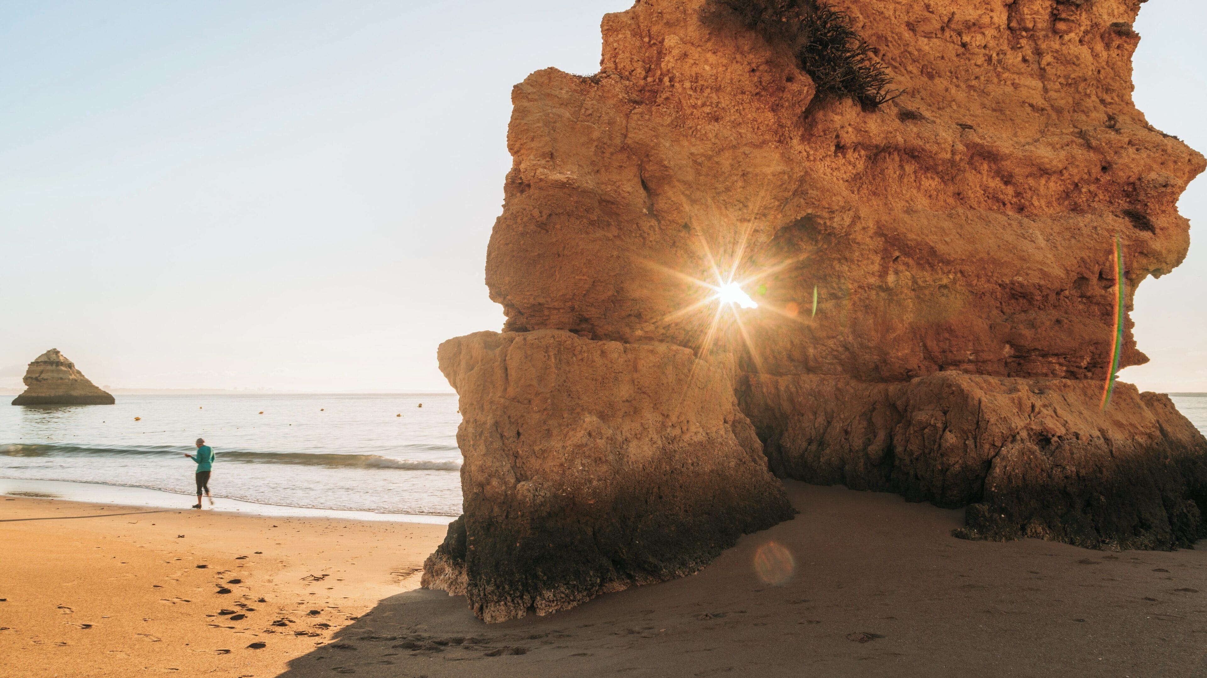 Beautiful sunset over Dona Ana Beach in Ameijeira, Lagos, Faro District, Portugal with a lone figure enjoying the coastal view