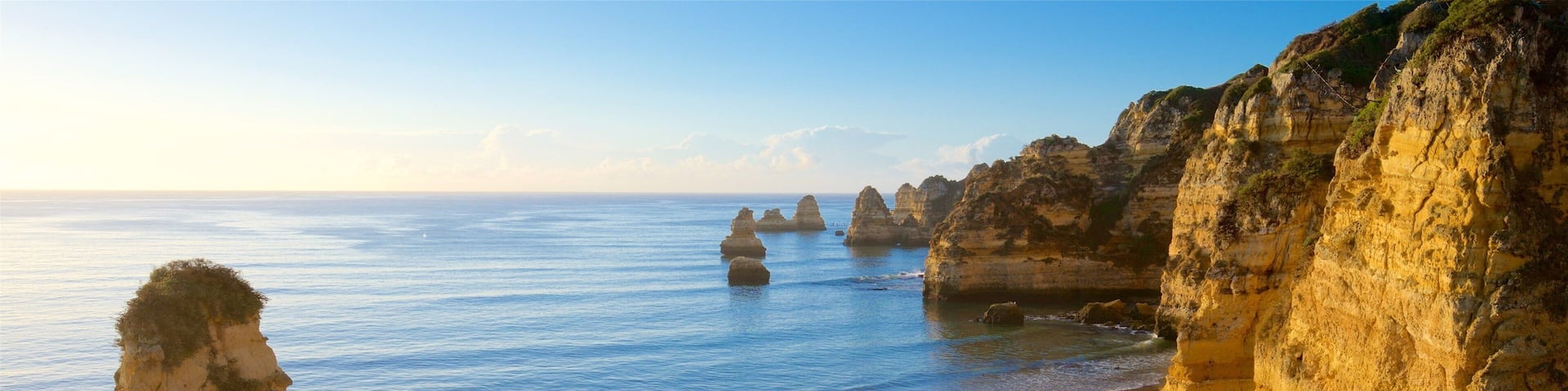 A beach with large rock formations and calm sea.
