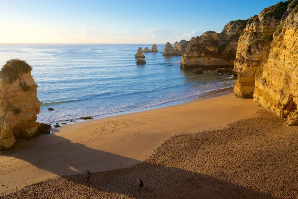 Una spiaggia con formazioni rocciose imponenti e mare calmo.