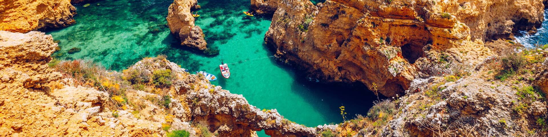 Panoramic view, Ponta da Piedade near Lagos in Algarve, Portugal. Cliff rocks and tourist boat on sea at Ponta da Piedade, Algarve region, Portugal. Ponta da Piedade, Algarve region, Portugal.